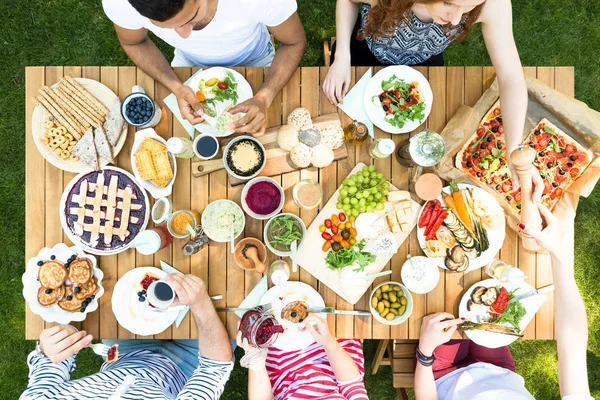 Pasta, pizza ve meyve Bahçe partisi sırasında ahşap masa üzerinde üstten görünüm