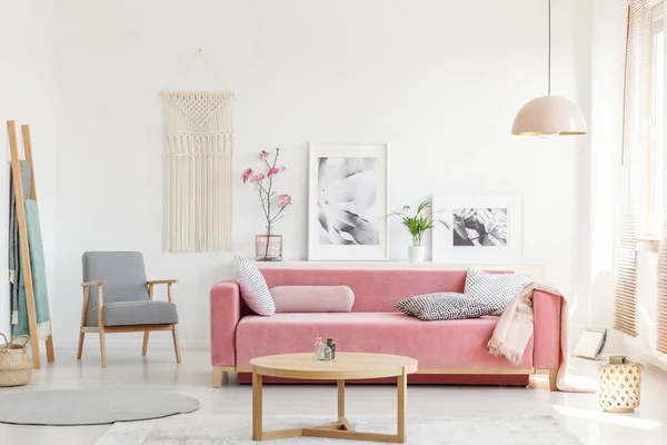 アパート インテリア ポスターと木製のテーブルでピンクのソファの横にあるパターンのアームチェア 実際の写真 — ストック写真