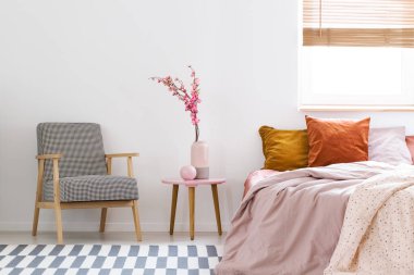 Çiçek desenli koltuk ve yatak odası iç pencere ile pembe yatak arasında masadaki. Gerçek fotoğraf