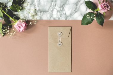 Kirli pembe ve mermer masa taze gül, kağıt zarf ve defter ve kalemler için boş alanlarda yüksek açı