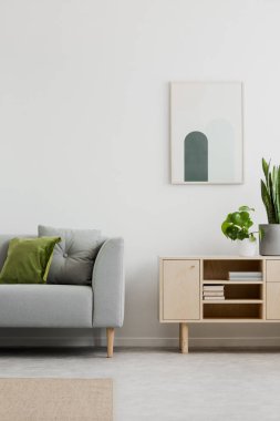 Poster gri kanepe ve bitkiler ile basit salon iç dolapta yukarıda. Gerçek fotoğraf