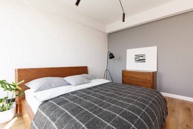 Gri desenli battaniye ahşap otel yatak odası iç kabine yukarıda posteri ile yatakta var. Gerçek fotoğraf