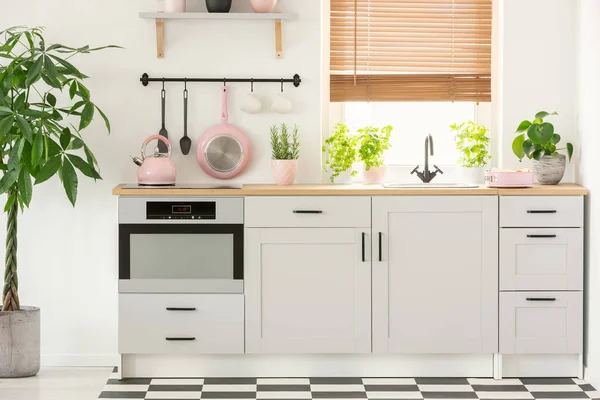 柔和的粉红色平底锅和水壶在一个美丽的厨房内部与简单 白色橱柜和水槽的窗口与百叶窗 — 图库照片