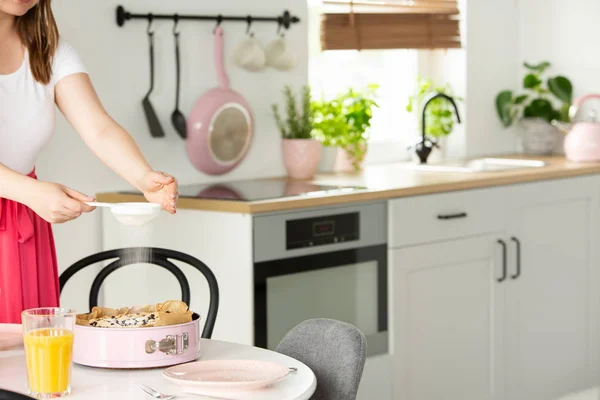 Frau Dekoriert Einen Kuchen Mit Puderzucker Rosa Backform Einem Kücheninnenraum — Stockfoto