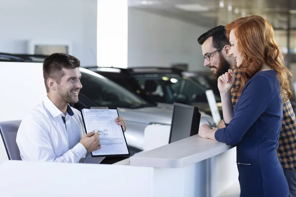 Smiling Car Dealer Showing Rental Agreement Buyers Showroom — Stock Photo, Image