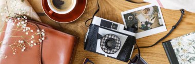 Bir fincan kahve ve bir deri çanta ile ahşap bir masa üzerinde bir vintage, film fotoğraf ve bir polaroid resim üstten görünüm