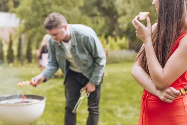 Mujer Feliz Comiendo Pan Mientras Amigo Asando Shashliks — Foto de Stock