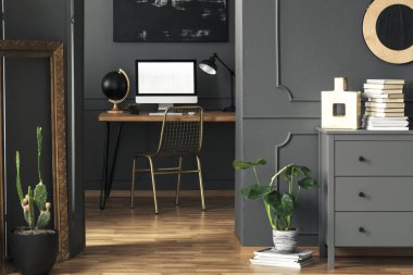 Karanlık oturma odası iç altın dekor, taze bitki ve ahşap masa mockup bilgisayar ile gerçek fotoğraf