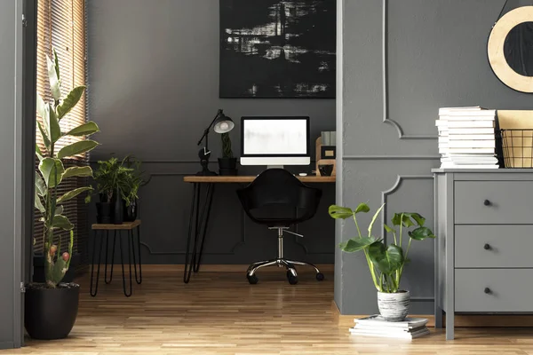 在办公桌上的黑色绘画与台灯和台式电脑在灰色公寓内部 真实照片 — 图库照片