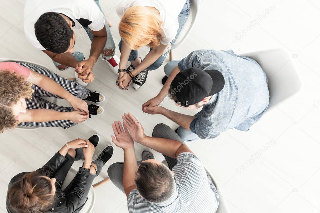 Top view on difficult youth talking to a therapist while sitting in a circle during meeting