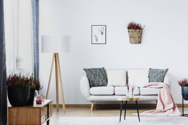 Büyük lamba ayakta beyaz bir kanepe yastıkları bir oturma odası iç ile yanında