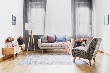 Bir lamba ve sofa ile yastık yanındaki bir dolap üzerinde heathers ile düz iç gri tekli
