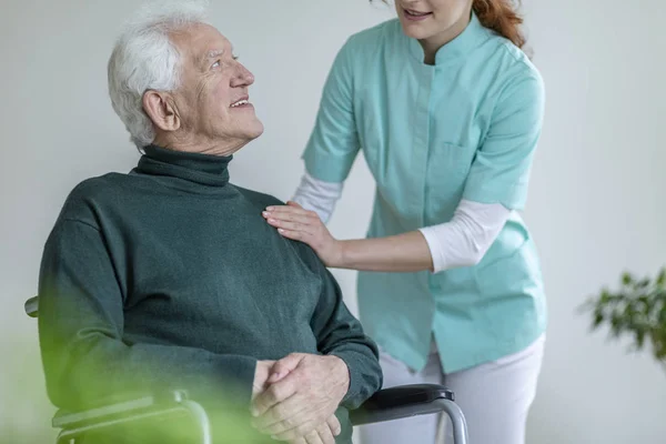 Cuidador Falando Com Homem Feliz Uma Cadeira Rodas Uma Casa — Fotografia de Stock