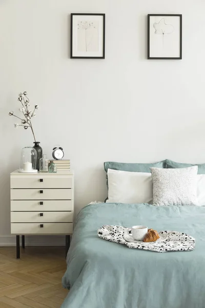 朝食の白い寝室インテリアの本物の写真が装飾付きベッドサイド テーブル つの単純なポスターとパステル グリーン寝具枕ベッドに配置されて — ストック写真