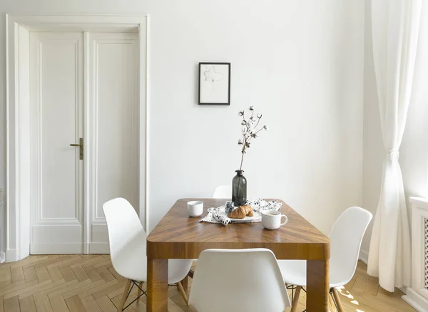 ドアとポスターと最小限のダイニング ルームのインテリアに木製のテーブルに白い椅子 実際の写真 — ストック写真