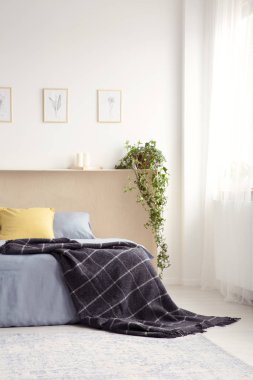 Beyaz yatak odası iç taze bitki, basit posterler ve pencere perde ile gerçek fotoğraf yatakta atılmış siyah paket