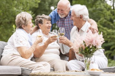 Happy and smiling senior people drinking wine on the terrace during summer clipart
