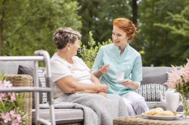 Gülümseyen hemşire terasta toplantı sırasında bir mutlu yaşlı kadınla konuşmak