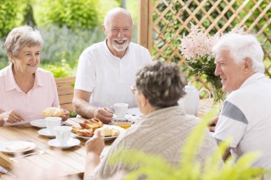 Happy and smiling senior people having fun while eating breakfast with friends clipart