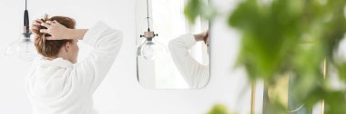 Beyaz saçları ile bitki bulanık ön planda fotoğraf parlak banyo iç ayna önünde ipe sabahlık kadında
