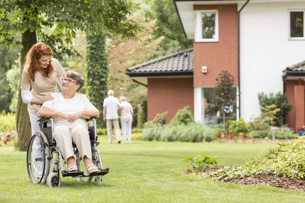 Sjuksköterska Stödja Funktionshindrade Senior Kvinna Rullstol Trädgården — Stockfoto