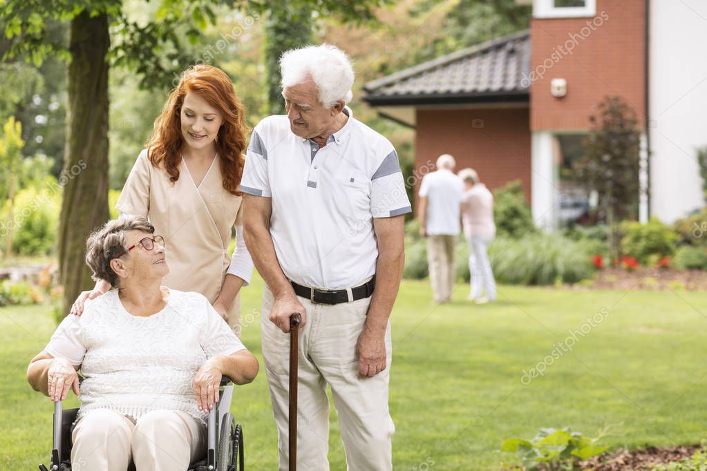 Nurse and grandmother in a wheelchair next to elderly man with walking stick