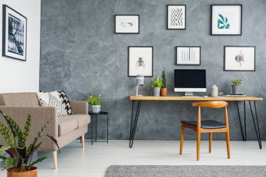 Kanepenin yanındaki ahşap Resepsiyon kahverengi ve gri freelancer'ın iç posterler ile sandalye. Gerçek fotoğraf