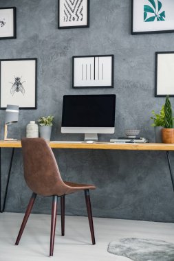 Basit resepsiyon ile bir bilgisayar ve bitki, resimler duvar ve bir ev ofis iç kahverengi sandalyede. Grafiğinizi buraya yerleştirin