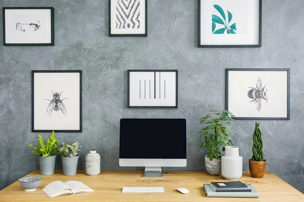 台式计算机在木桌与植物在灰色工作区内部与海报 真实照片 — 图库照片