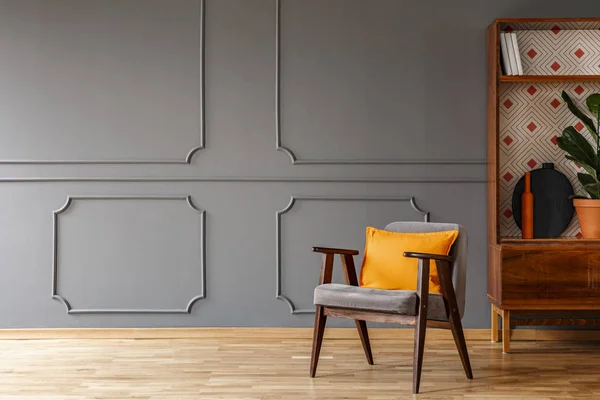 灰色扶手椅与橙色枕头站在真正的照片深灰色客厅内部与护墙板在墙上 空的空间为您的咖啡桌 — 图库照片
