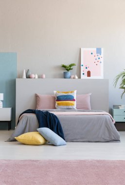 Bir battaniye renkli yatak odası iç poster ve bitki yatak başı üzerinde ile yatakta var. Gerçek fotoğraf