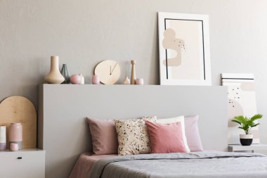 Gri yatak odası iç üretim tesisi ile pembe yastık yatak yatak başı üzerine poster. Gerçek fotoğraf