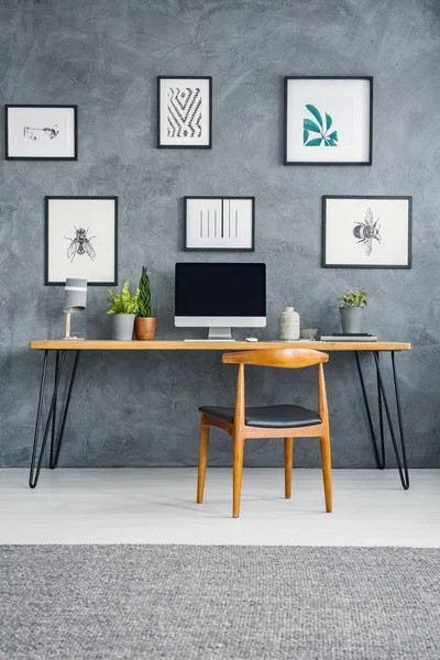 Holzstuhl Schreibtisch Mit Desktop Computer Vor Grauer Wand Mit Postern — Stockfoto