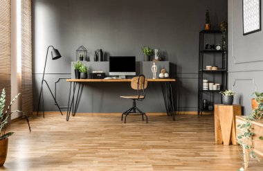 Bilgisayar monitörü ve gri geniş ev ofis iç bitkilerde ahşap masa sandalye