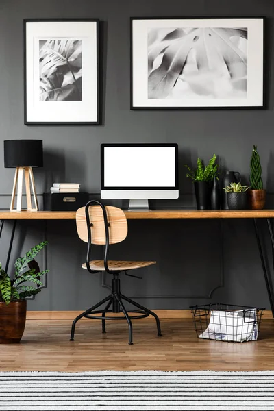 灰色の壁にポスターと木製ホーム オフィス インテリアで空のコンピューター モニターのモックアップ — ストック写真