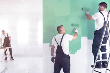 Bitirme ise yeşil ve bir merdiven üzerinde ayakta duran bir duvar boyama işçi iç