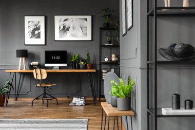 Bitkiler ile bilgisayar monitörü masası yukarıda posterler ile gri ev ofis iç ahşap tablo