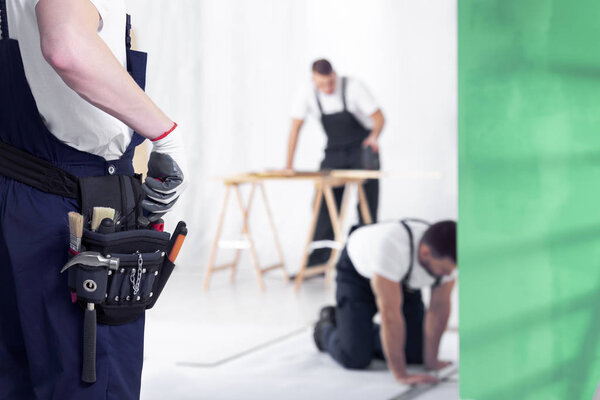 Close-up of craftsman with toolbelt during home renovation work. Blurred background