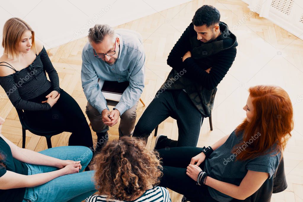 High angle of a group of teenagers sitting in a circle during psychotherapy
