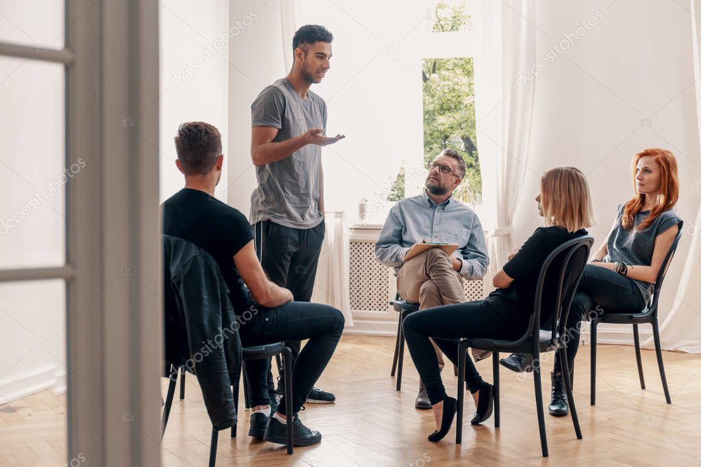 Spanish man talking to rebellious teenagers during meeting of support group