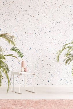 Beyaz masa süslemeleri, bitkiler ve pastel kilim desenli duvar aydınlık oturma odası iç. Koltuk için bir yer ile gerçek fotoğraf