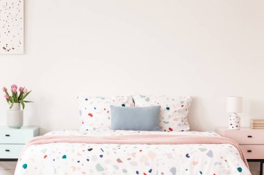 Bir çift kişilik yatak ile noktalı çarşaflar ve yastıklar nightstands bir yatak odası iç arasında boş bir duvar üzerinde gerçek fotoğraf. Resim için yer