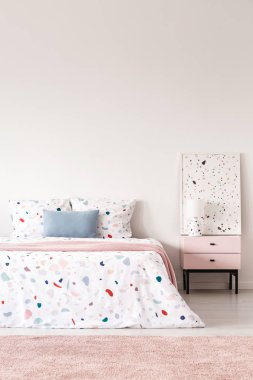 Mavi yastık pembe halı ve poster ile beyaz yatak odası iç desenli yatakta. Gerçek fotoğraf