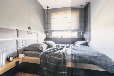 Desenli battaniye var gri parlak yatak odası iç pencere ve lamba ile yatakta. Gerçek fotoğraf