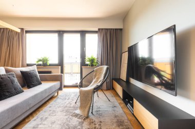 Battaniye var siyah tekli dolap ve aydınlık oturma odası iç gri kanepe arasında. Gerçek fotoğraf