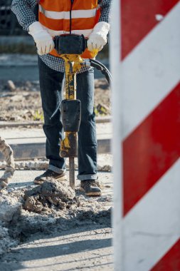 İşçi yansıtıcı yelek ve asfalt roadworks sırasında tamiri matkap ile