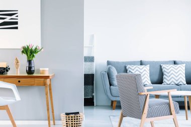 Gerçek fotoğraf gri ve beyaz pembe laleler ve iki yastıkları kanepeyle olan alan oturma odası iç desenli koltuk ile ahşap resepsiyon açık