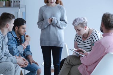 Ayakta ve onların danışman ile bir toplantı sırasında bir grup terapisi diğer katılımcılar ile onun hikayesi paylaşımı utangaç çekilen genç kız.