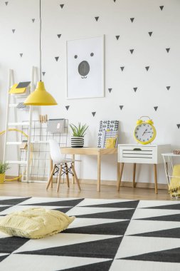 Çocuğun oda iç masada beyaz sandalye ile geometrik halı üzerinde sarı yastık. Gerçek fotoğraf