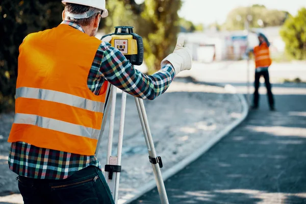 Engineer Reflective Vest Using Equipment Geodetic Work Blurred Colleague Background — Stock Photo, Image